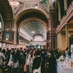 A view of a packed expo hall, with various booths and many attendees.