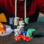 A person sitting in front of several stacks of poker chips while peeking at his cards.