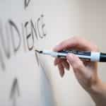 Close up of female hand writing the word audience on whiteboard.