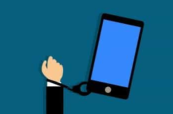 A person’s arm handcuffed to a large smartphone.