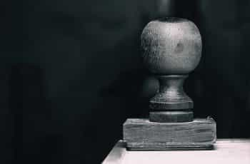 A wooden stamp or seal resting on its face on the edge of a table.