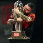 Michael Smith clutches the PDC World Darts Championship trophy he won in 2023.