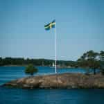 A flag on a rock in the middle of a water body.