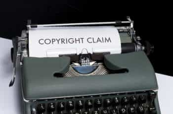 An old-fashioned typewriter sitting on a table, with the words “Copyright Claim” written in large font on the sheet of paper sticking out of the machine.