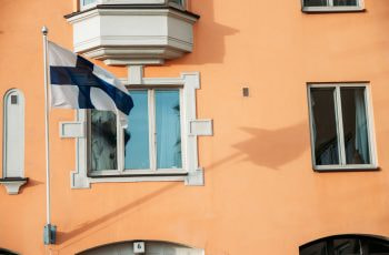 An unfurled flag in the wind against a blue sky.